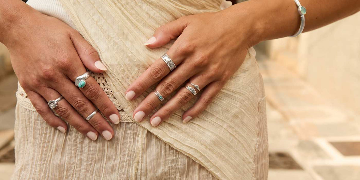 Manos con varios anillos de plata combinados, con turquesas, de San Saru